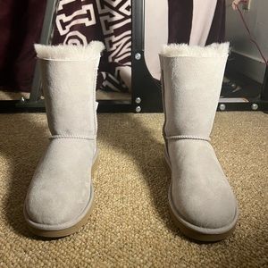 Light gray/mauve Ugg boots with two bow ties in the back of the boot.